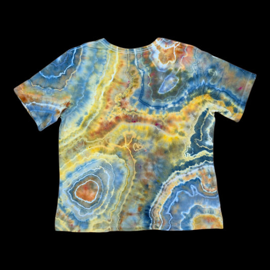 Back of the same tee with banded geode rings and a cream-and-orange bullseye near the hem in blue, yellow, and copper.