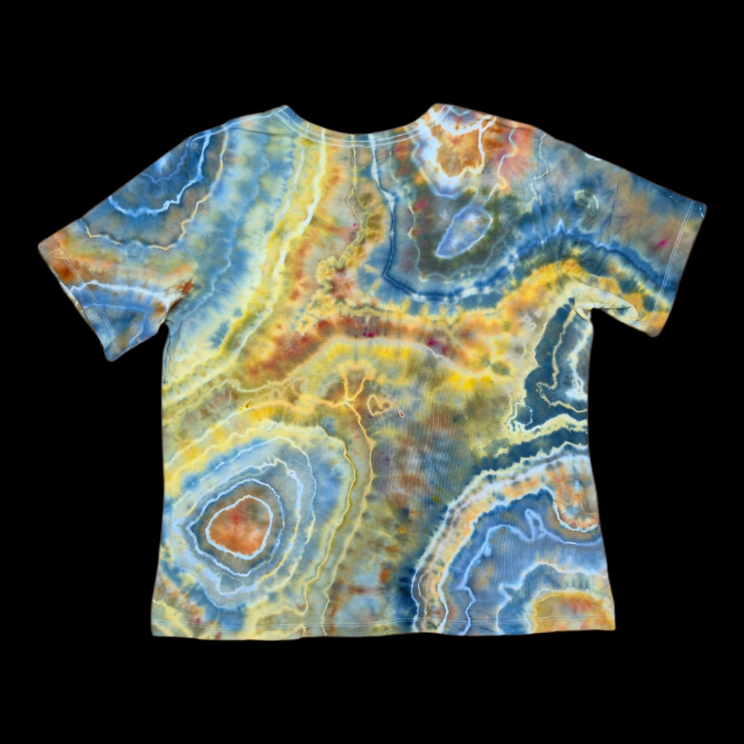 Back of the same tee with banded geode rings and a cream-and-orange bullseye near the hem in blue, yellow, and copper.