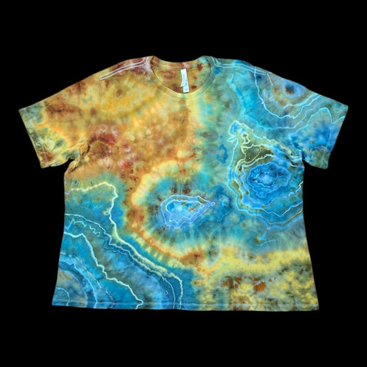Front of a relaxed tie-dye tee with concentric geode rings in turquoise, teal, gold, and rust brown.