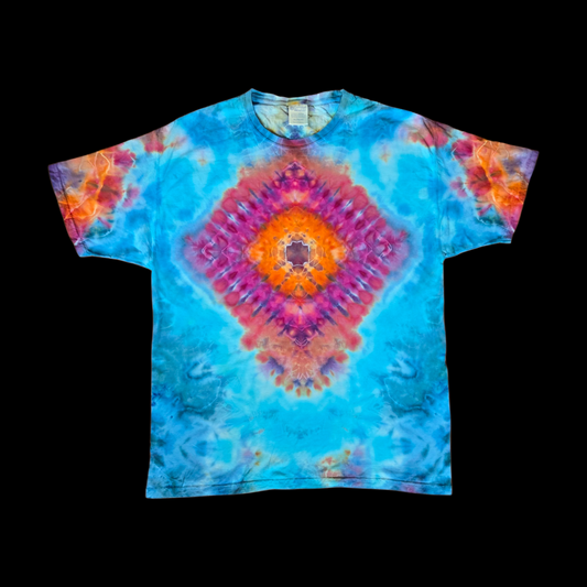 Front of a tie-dye tee with a centered diamond mandala in pink, magenta, orange, and purple on a turquoise and blue background.