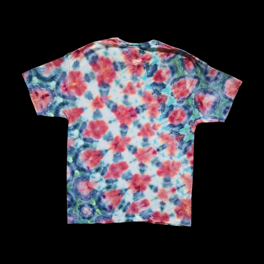 Back of the tee showing the same allover shibori-inspired arrangement of red and pink centers ringed by navy blue with green and teal accents.