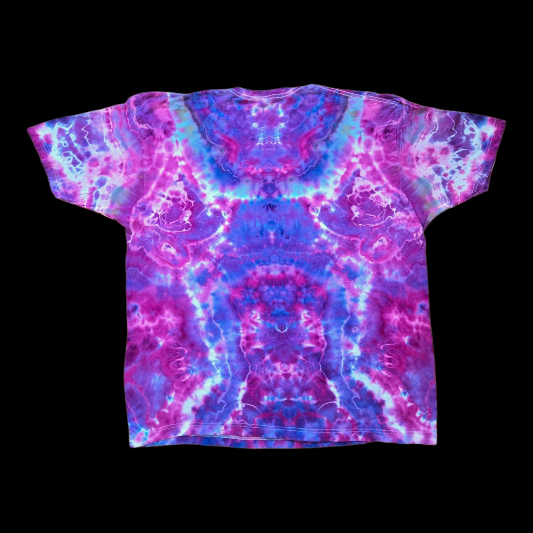 Back of the same t-shirt showing a symmetrical ice dye pattern in magenta, purple, blue, and white mirrored across the center.