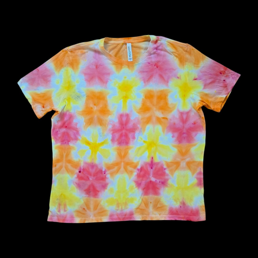 Front of a women's relaxed tee with a repeating triangle-fold shibori grid of mirrored pink, orange, and yellow shapes outlined in white.
