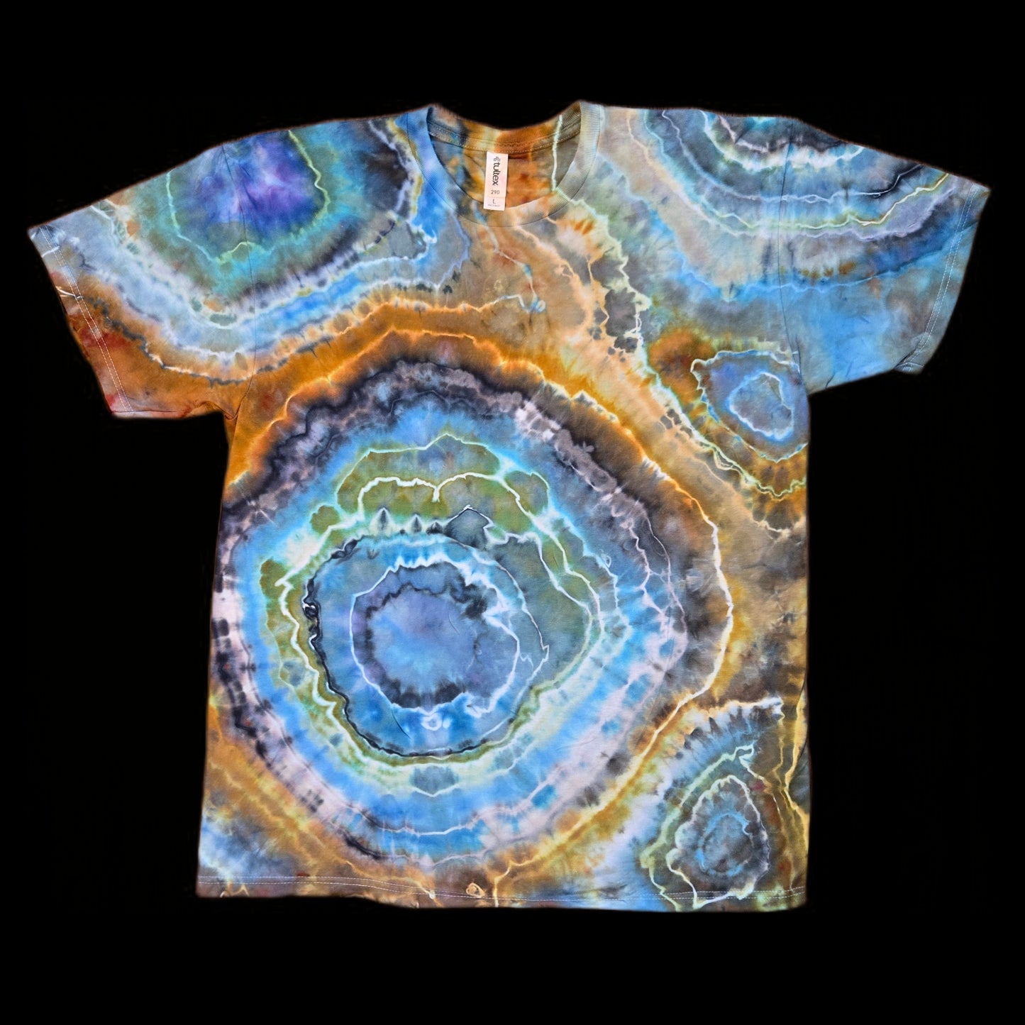 Front of a tie-dyed t-shirt with large concentric geode rings in blue, orange, gray, and green on a black background.