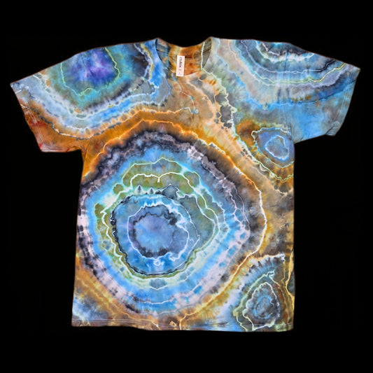 Front of a tie-dyed t-shirt with large concentric geode rings in blue, orange, gray, and green on a black background.