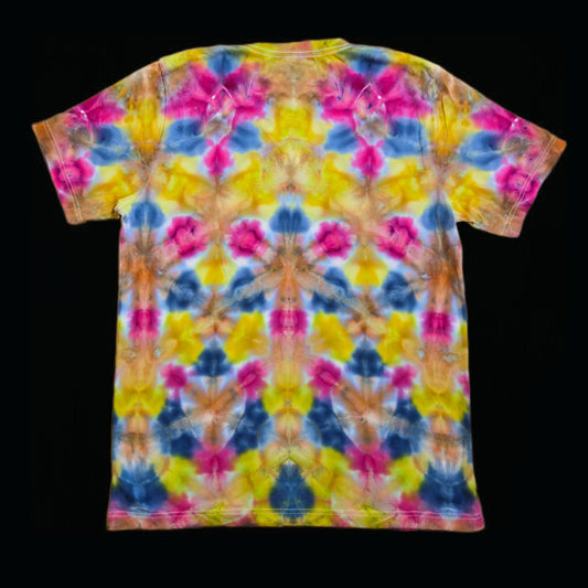 Back of the same t-shirt showing the mirrored fold tie-dye repeat in magenta, yellow, blue, and orange with symmetry along the center spine.